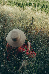 Woman with straw hat sitting in a wild flowers field