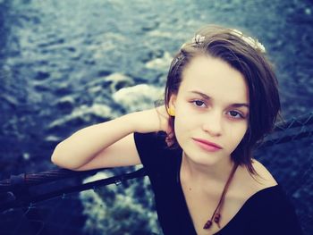 Portrait of teenage girl standing against river