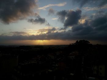 Cityscape against cloudy sky at sunset