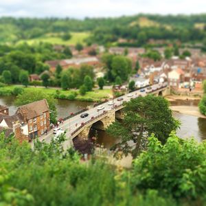 Tilt-shift image of river by town against sky