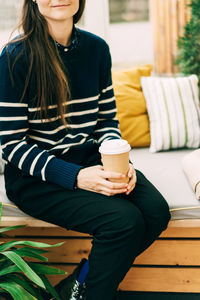 Midsection of woman holding coffee cup