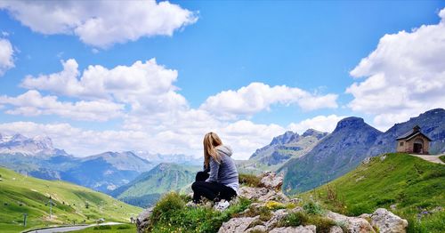 Side view of mature woman sitting on mountain against cloudy sky