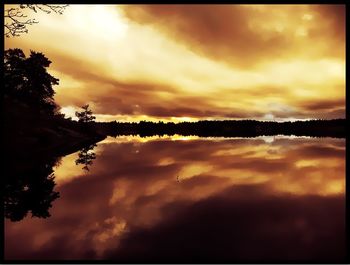 Scenic view of landscape against cloudy sky at sunset