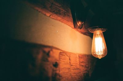 Close-up of illuminated light bulb against wall