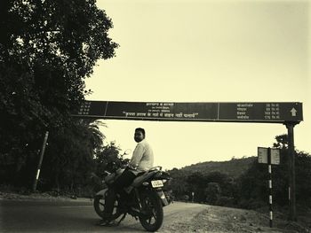 Rear view of man riding motorcycle on road against sky