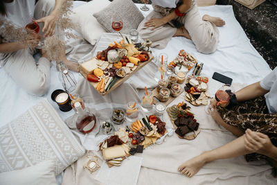 Young women having food and drink while sitting on blanket on building terrace