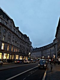 Cars on city street against sky