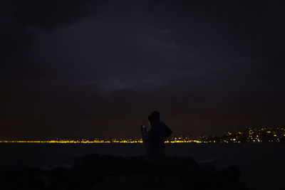 Full length of man standing by sea against sky at night