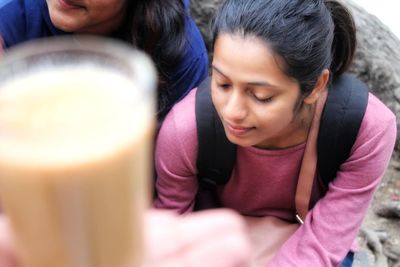 Close-up of a smiling girl sitting with drink