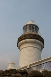 Low angle view of lighthouse by building against sky