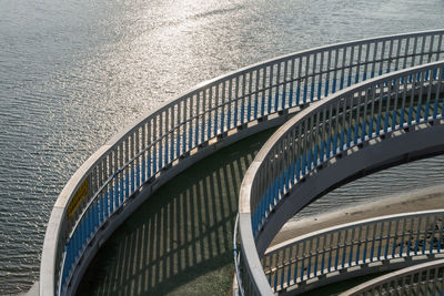 High angle view of curvy bridge by sea on sunny day