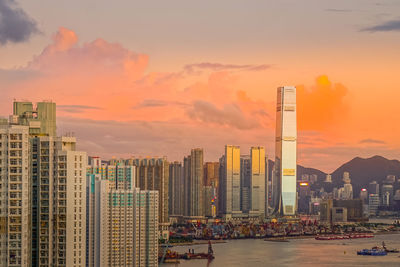 Modern buildings in city against sky during sunset