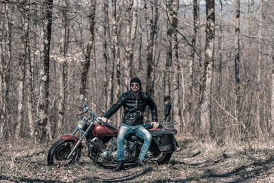 Mid adult man sitting on motorcycle in forest