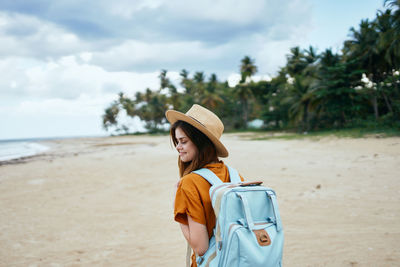 Woman wearing hat while sitting on beach