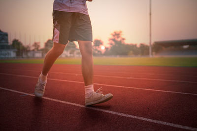 Low section of man running on track during sunset