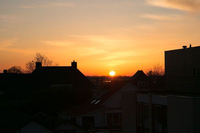 Silhouette buildings in town against sky during sunset