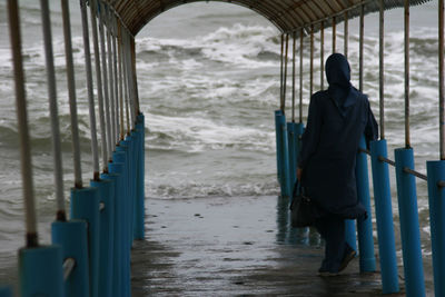 Rear view of woman standing below arch at beach