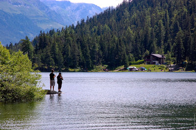 People fishing at lake by mountains