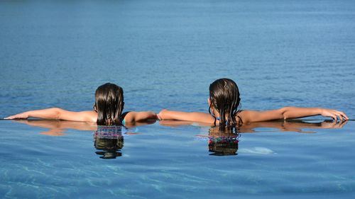 Rear view of girls in infinity pool against sea