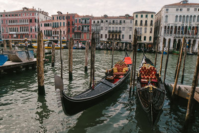 Gondola boats moored in canal against buildings and sky