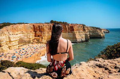 Rear view of woman looking at sea against clear sky