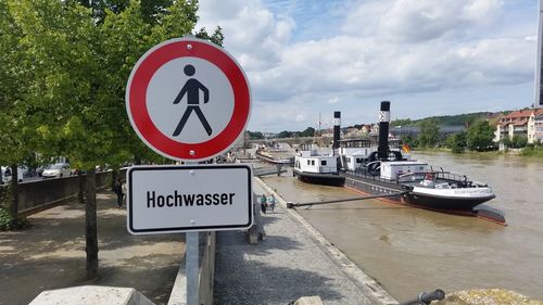 Information sign by river against sky