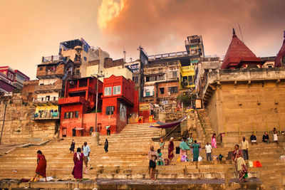 Group of people on building against cloudy sky