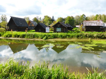 Houses by lake and buildings against sky