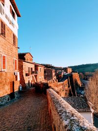 Alley amidst buildings in town against clear blue sky