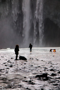 Silhouette people standing in sea against sky