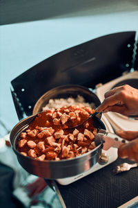 Close up of female hands putting dish with tomato sauce. woman cooking meal on electric stove