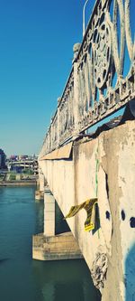 Built structure by river against clear blue sky