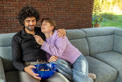 Portrait of smiling friends sitting on sofa at home