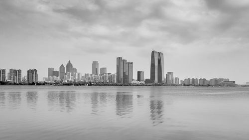 Sea and buildings in city against sky