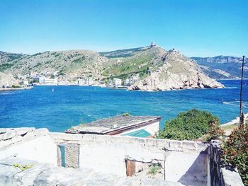 Scenic view of sea by buildings against clear blue sky