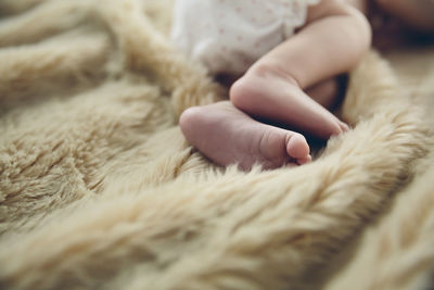 Low section of baby girl lying on bed at home