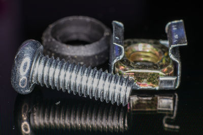 Close-up of metallic screw and hinge against black background