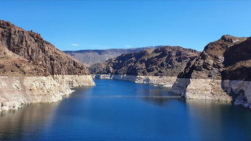 Scenic view of lake and mountains against clear blue sky