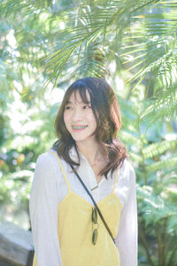 Young woman standing against plants