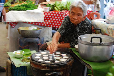 Senior woman preparing food at street market