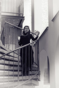 Portrait of woman standing against staircase