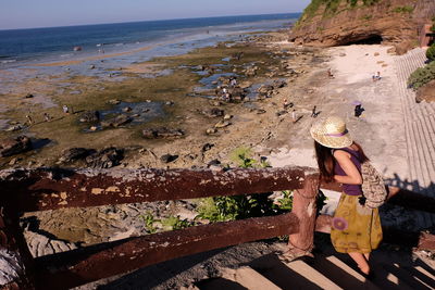 Rear view of woman on steps against beach