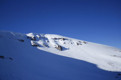 Aerial view of snowcapped mountain against clear blue sky