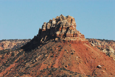 Rock formations on landscape against clear blue sky