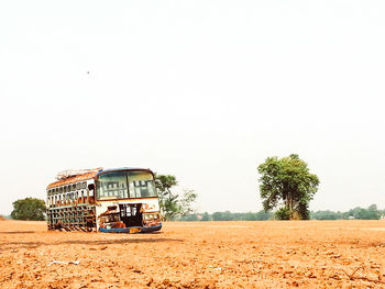 Abandoned bus on field against clear sky