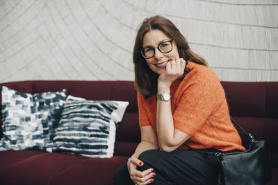 Portrait of smiling mature businesswoman sitting on couch at office