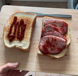 High angle view of hand holding bread on cutting board