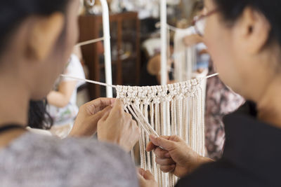 Close-up of women weaving string at workshop