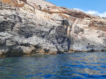 Rock formations by sea against sky