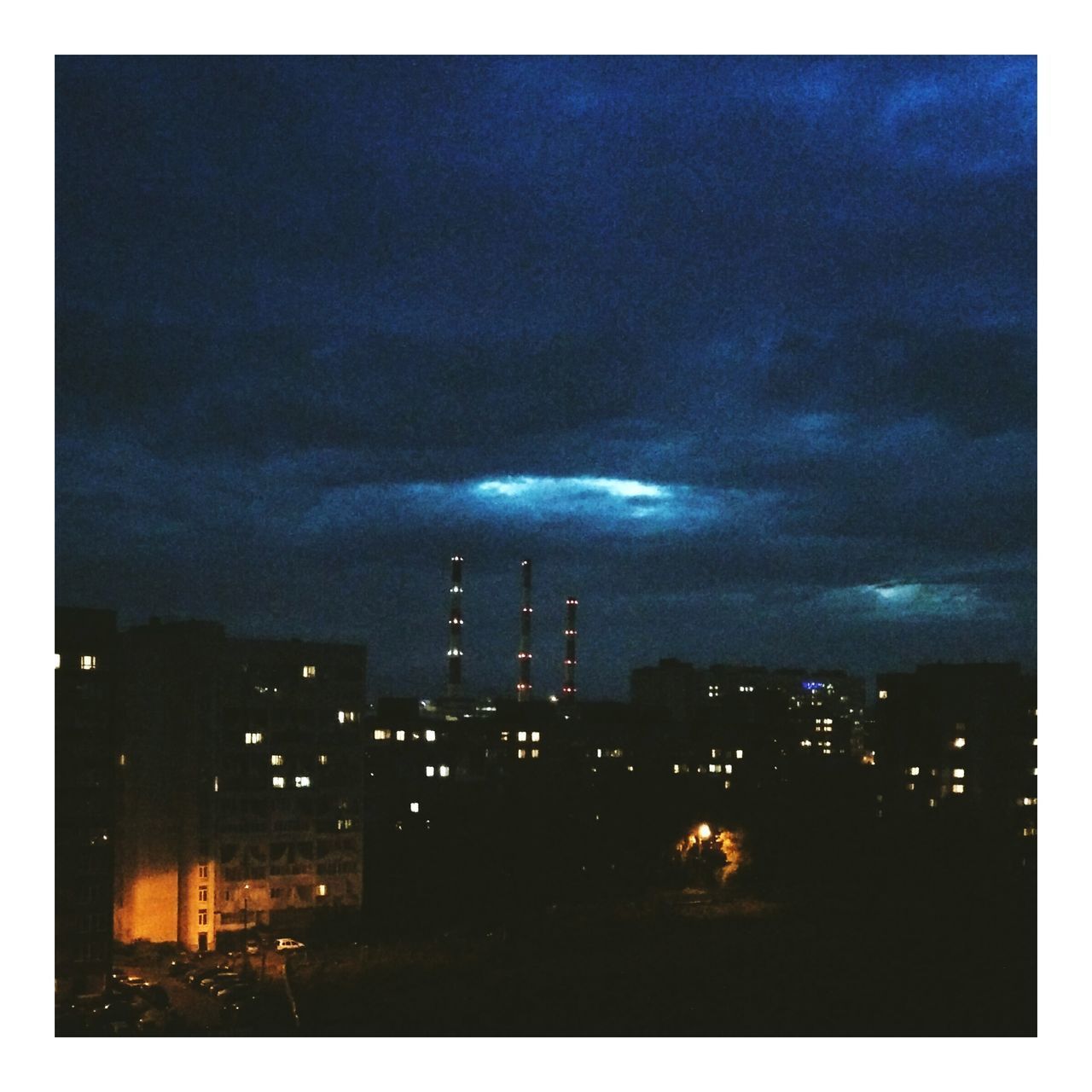 ILLUMINATED MODERN BUILDINGS AGAINST SKY AT NIGHT